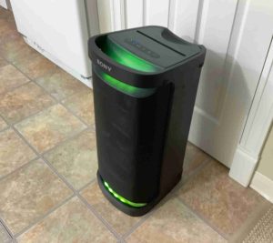 Picture of the left front of the Sony SRS XP700 speaker, showing its party lights glowing green.